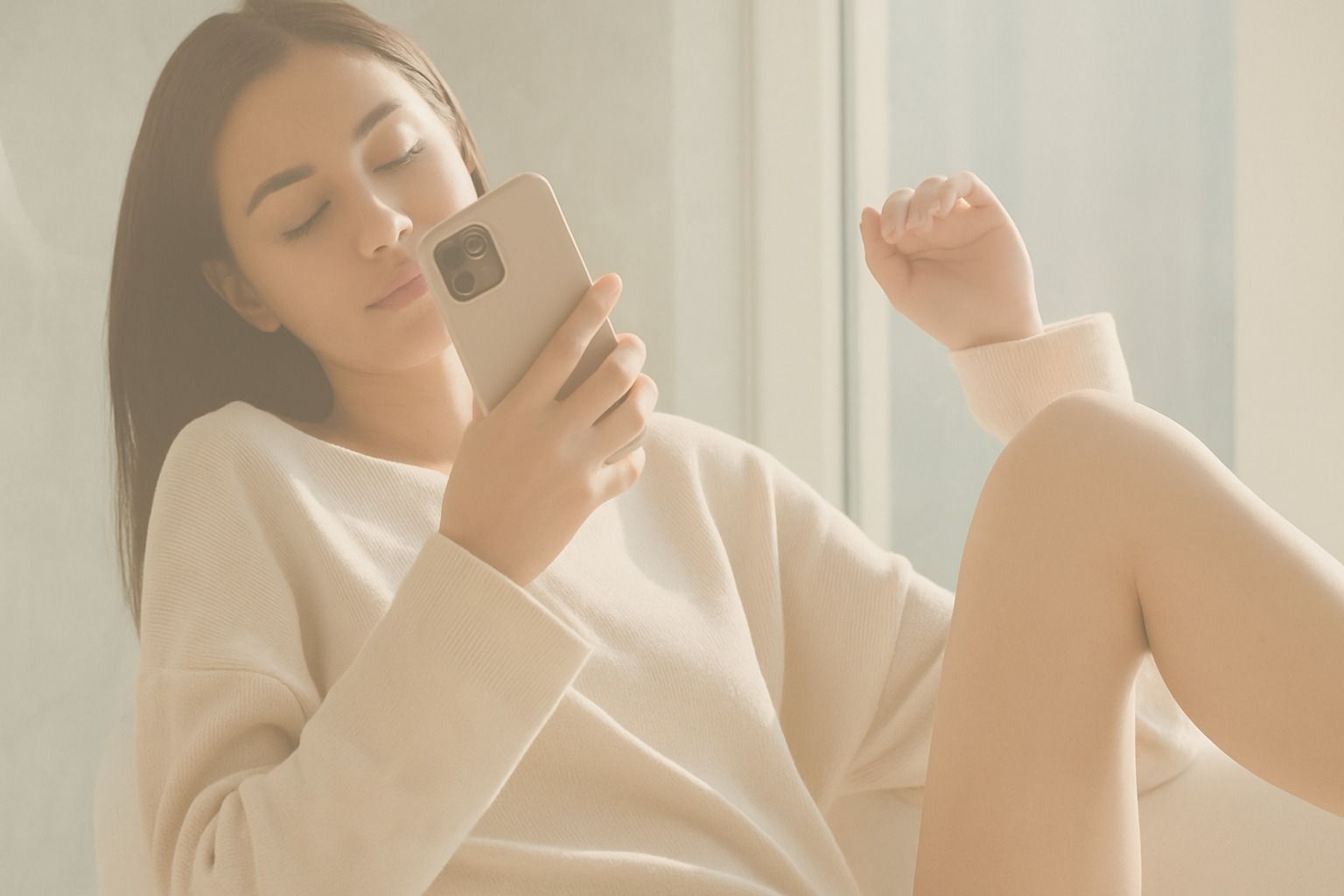Woman sitting, using smartphone in cozy setting.