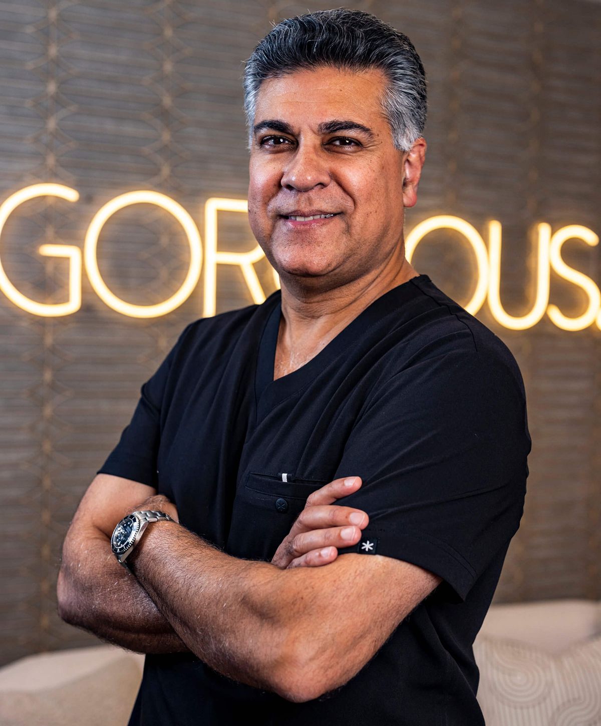 Male professional in black attire, smiling confidently.