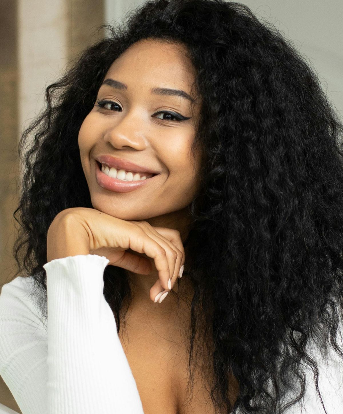 Smiling woman with curly hair and white top.