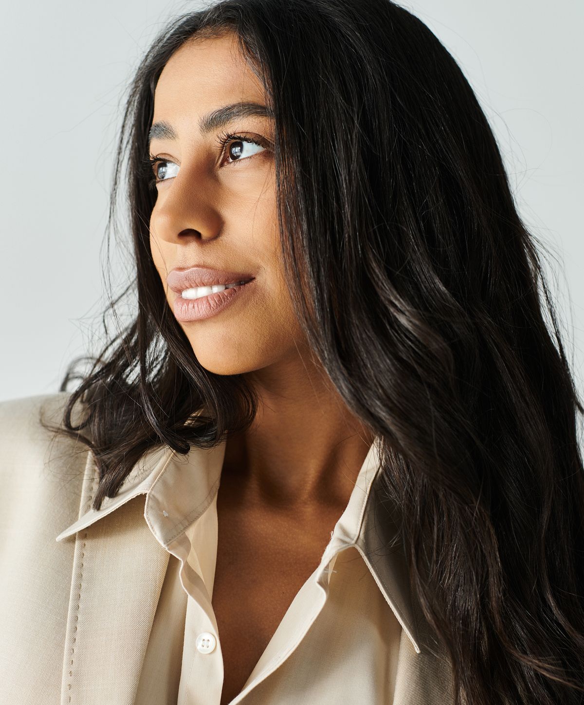 Smiling woman with long black hair outdoors.