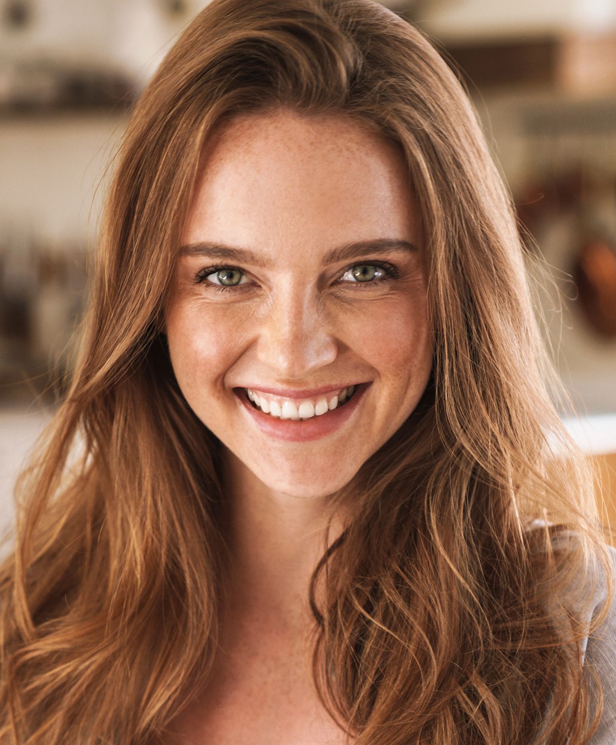 Smiling woman with long wavy hair indoors.