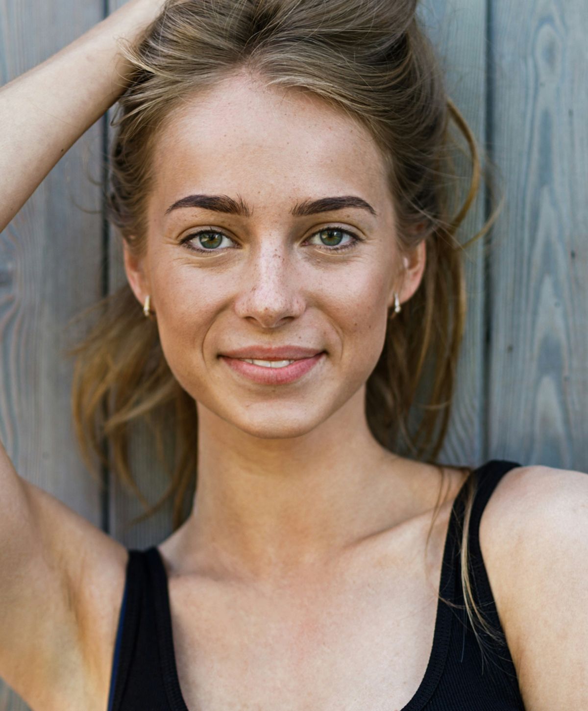 Smiling person with long hair against wooden background.
