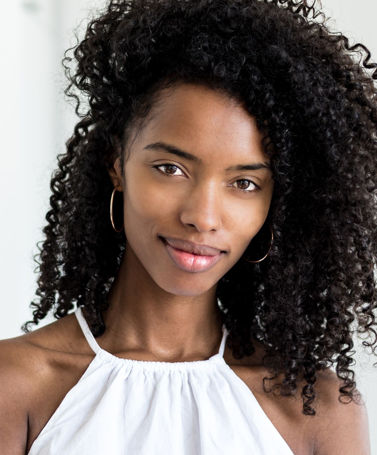 Smiling woman with curly hair and natural makeup.