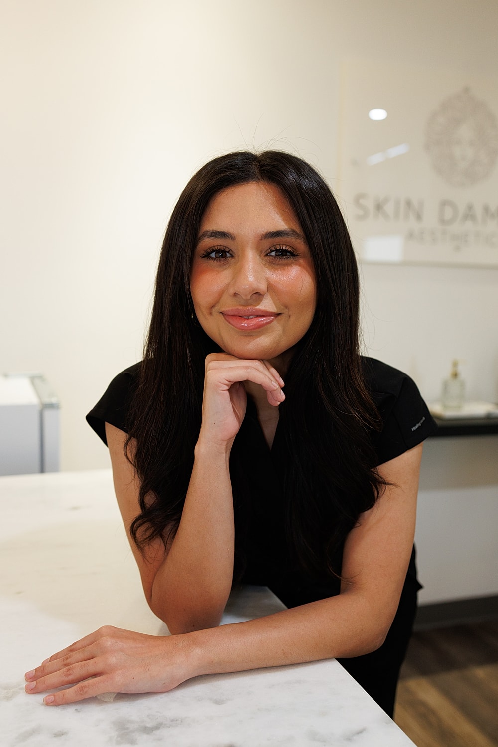Smiling woman in casual attire with illuminated sign.