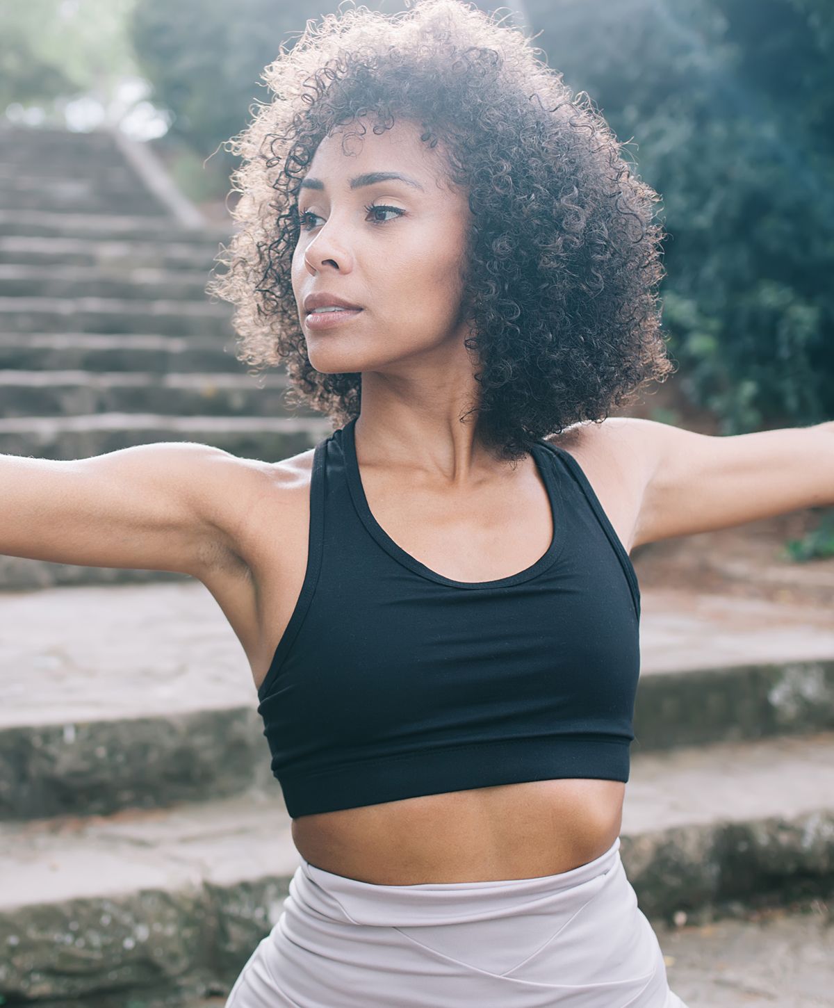 Woman exercising outdoors with arms extended.