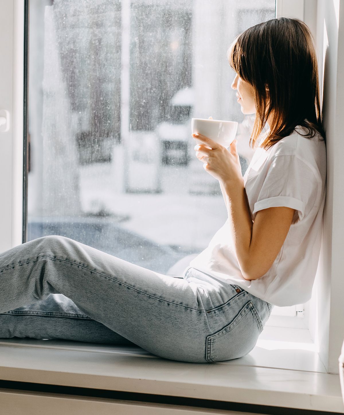 Person enjoying a warm drink by the window.