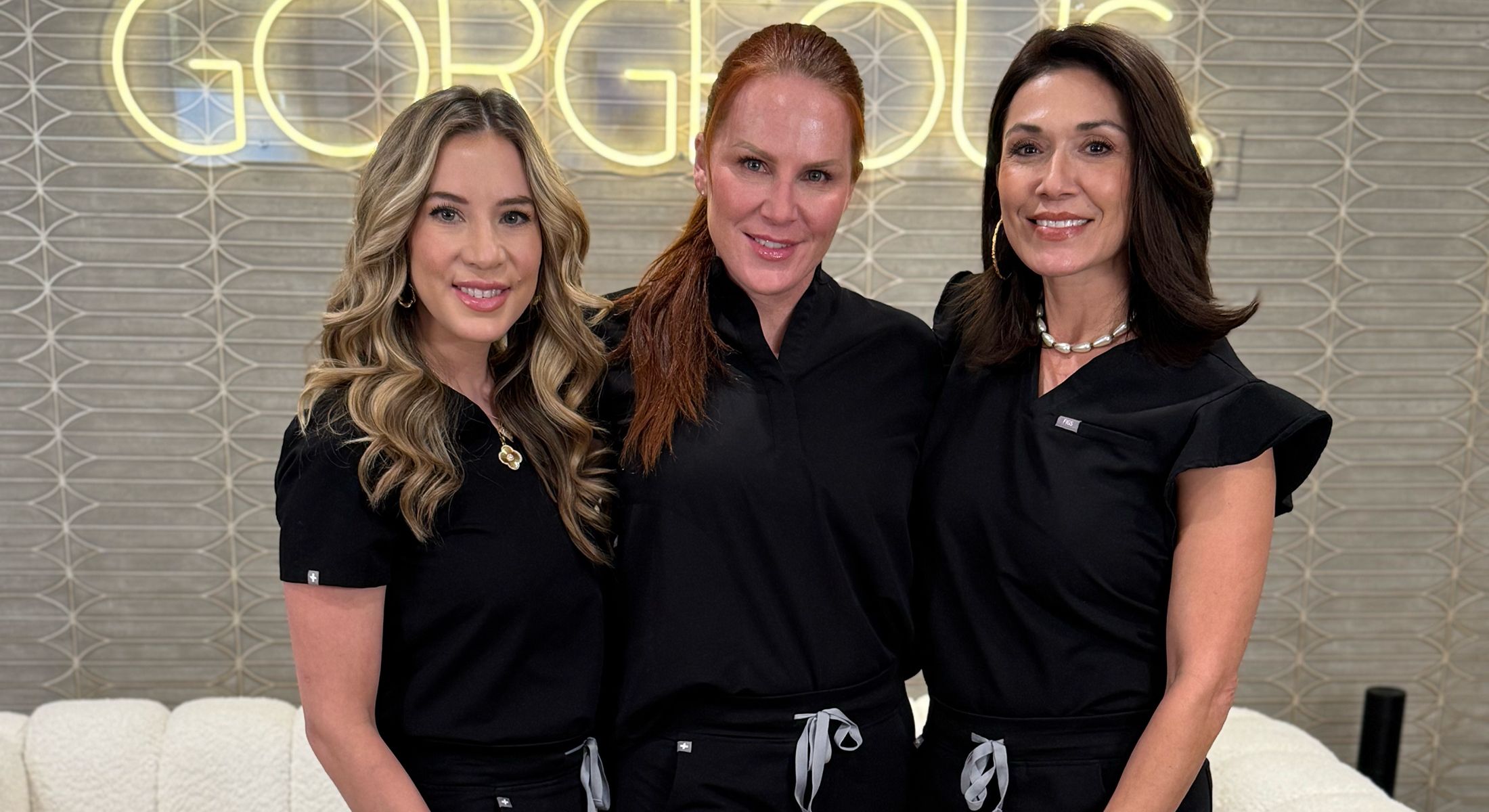 Three women posing in black outfits.