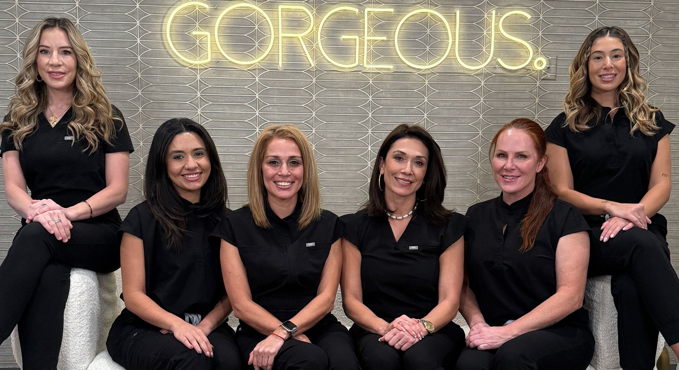 Group of professionals in black attire smiling.