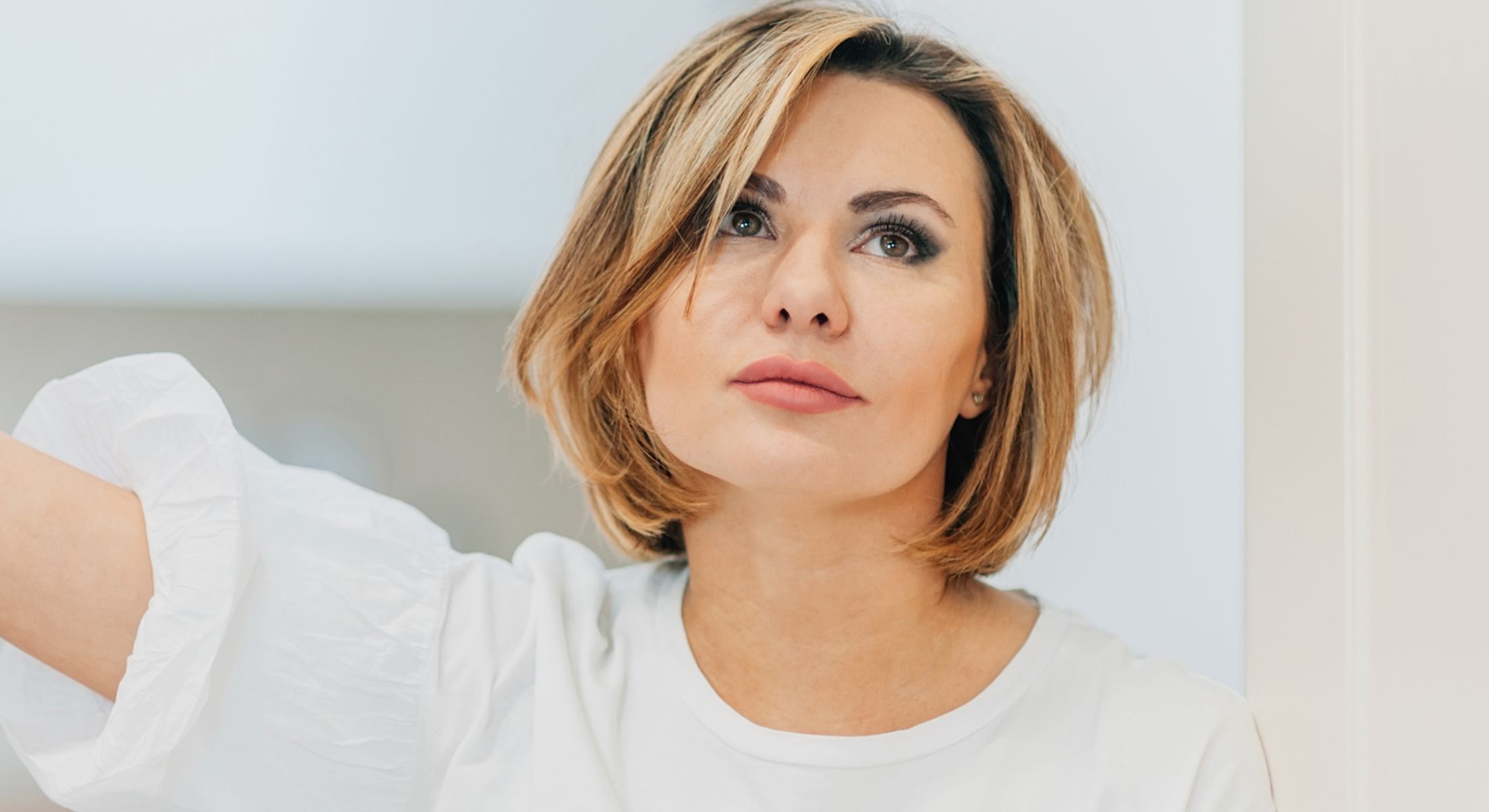 Woman with short hair looking thoughtfully upward.