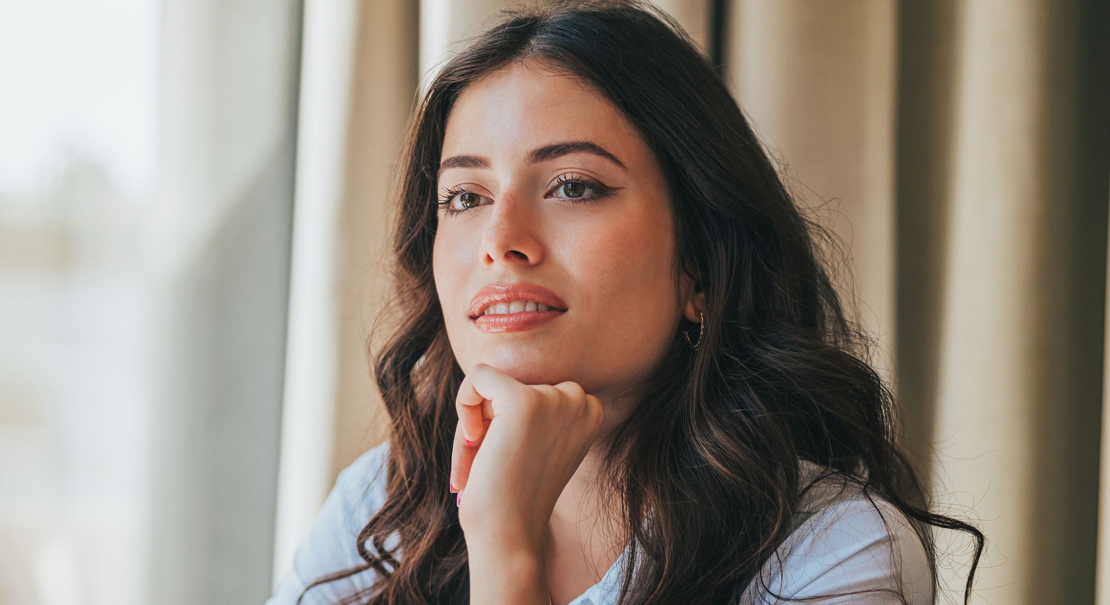 Woman thoughtfully resting her chin on hand.
