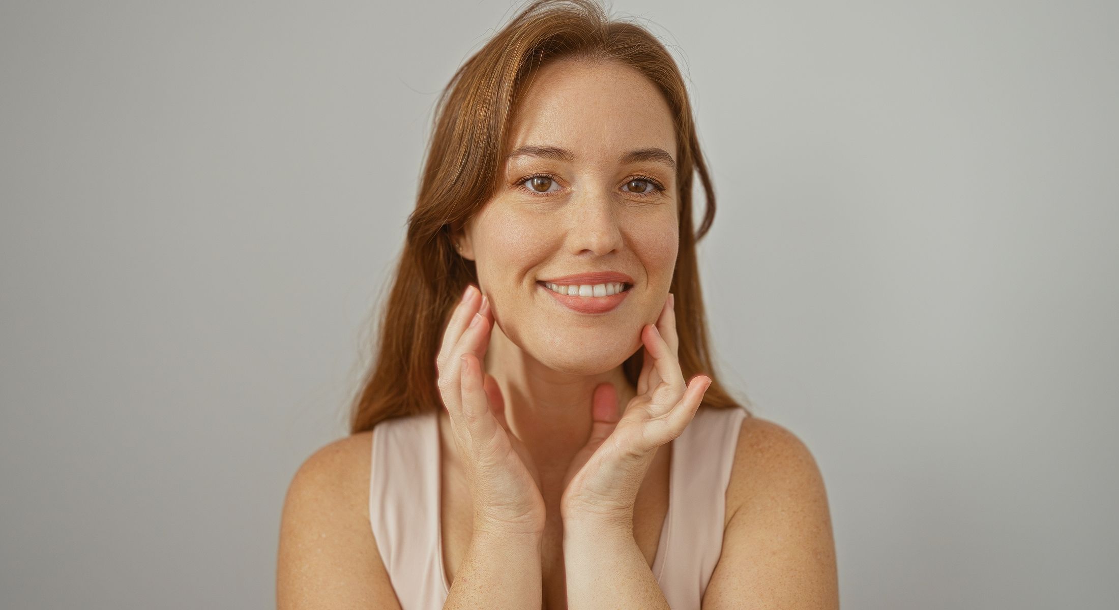Smiling woman touching her face gently.