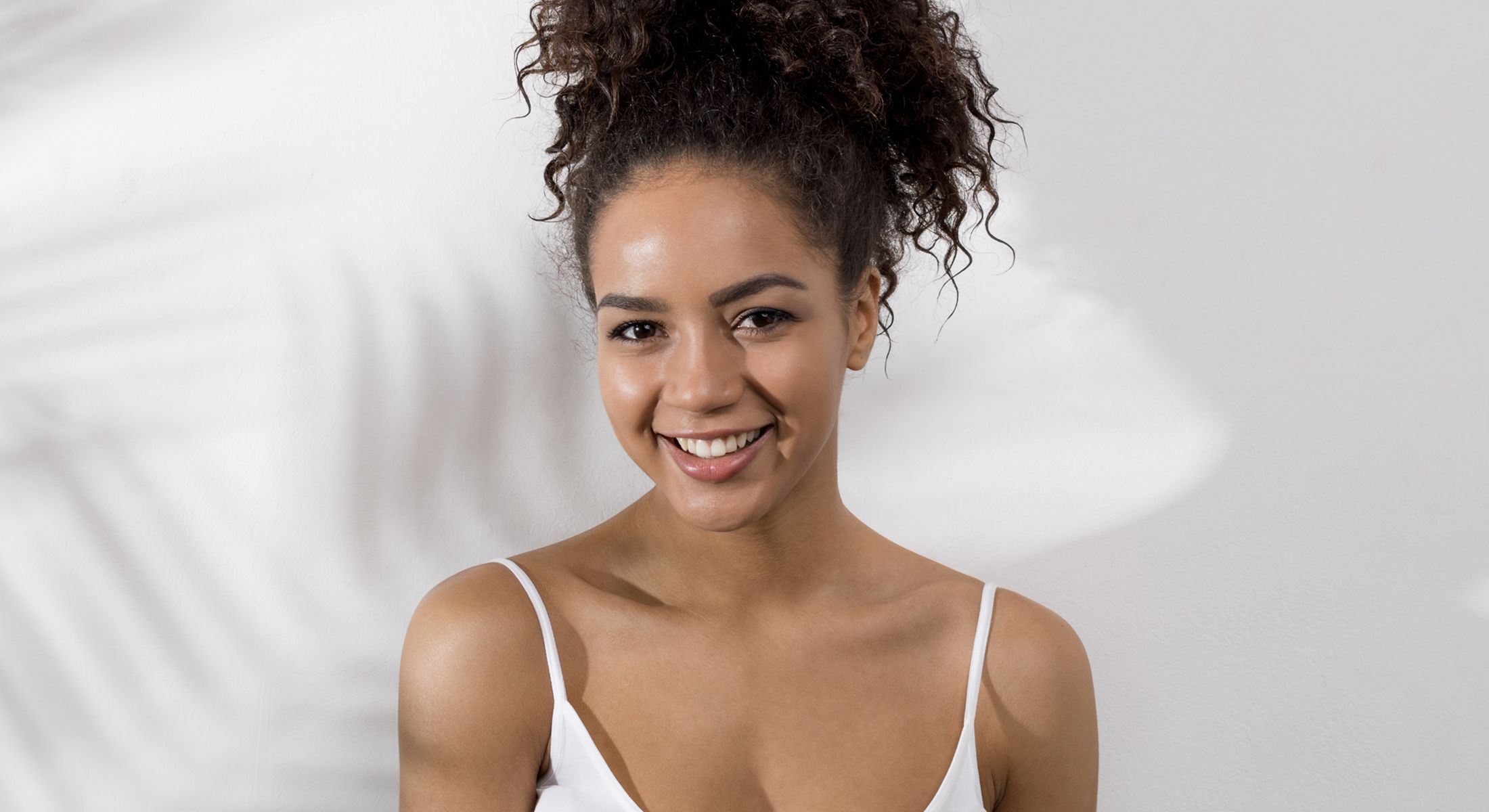 Smiling woman with curly hair against white background.