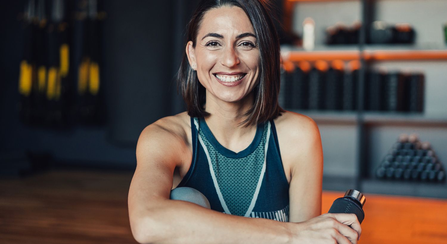 Smiling woman in gym, fitness lifestyle portrait.